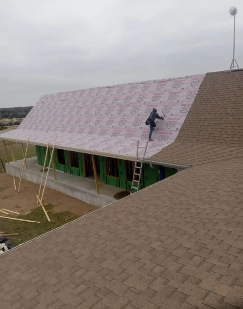 Worker preparing underlayment for a metal roof installation in San Marcos